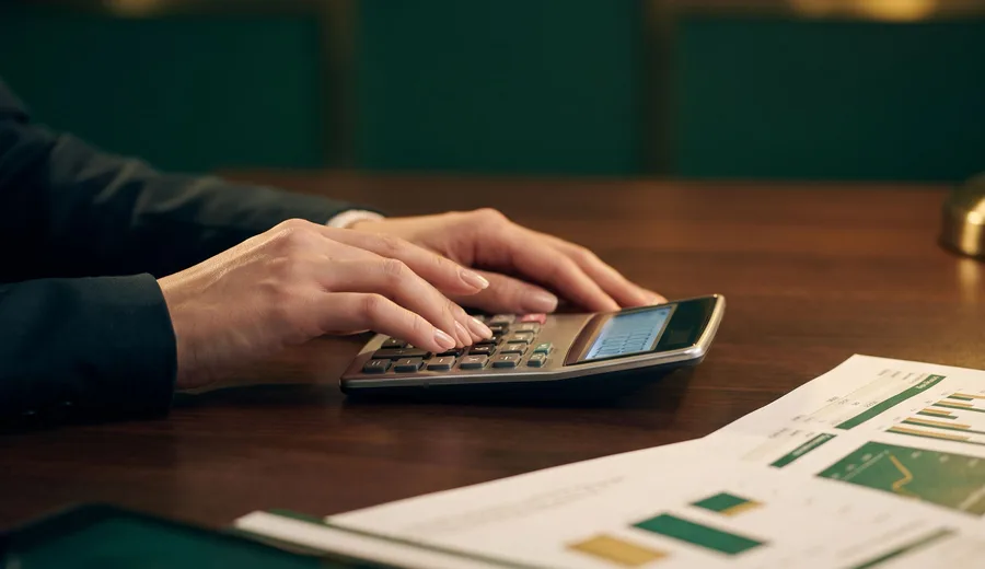 Calculadora e relatório com gráficos financeiros sobre mesa escura